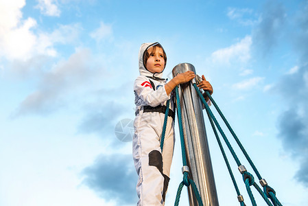 穿宇航员服装的男孩从攀爬架顶部远望图片