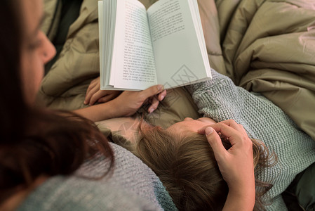 女孩躺在母亲身边看书图片