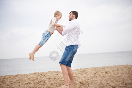 父亲在海滩上抱着儿子转圈圈图片