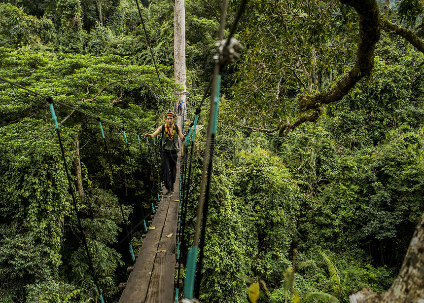 森林中跨越绳桥的男子图片