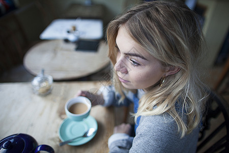 坐在咖啡馆喝咖啡面露深思的年轻女子图片