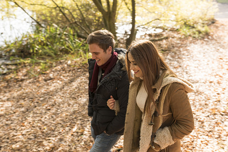 年轻夫妇在公园中行走手抱臂微笑约会高清图片素材