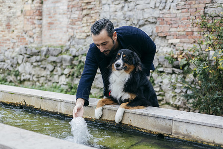 成年男子带着狗狗在水槽中洒水高清图片