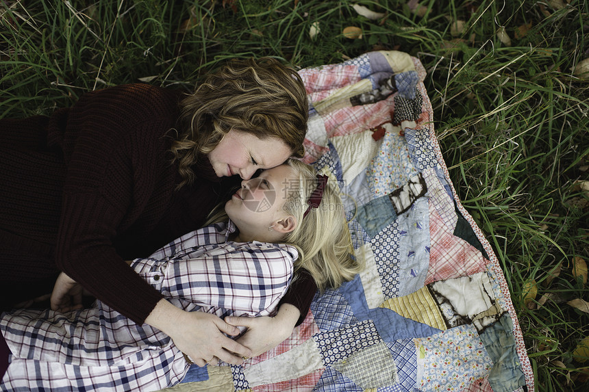 母亲和女儿躺在毯子上面对面拥抱图片