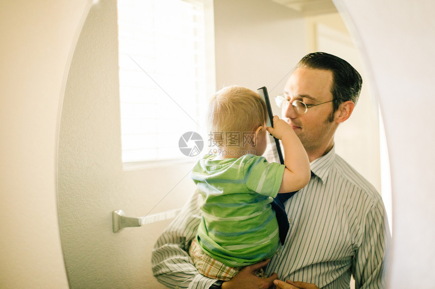 父亲抱小儿子梳头发镜中反射图片