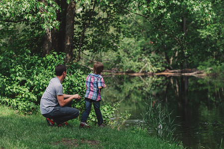 男孩和父亲从森林河岸寻找图片