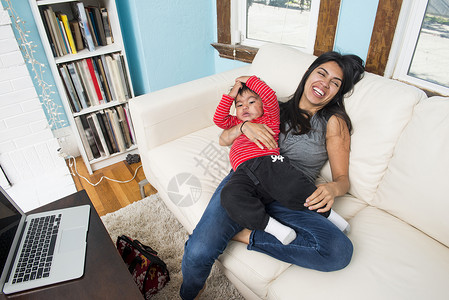 抱着儿子坐在沙发上笑的女人背景图片