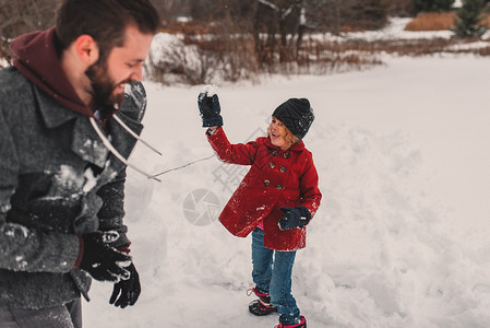 女孩向父亲扔雪球图片