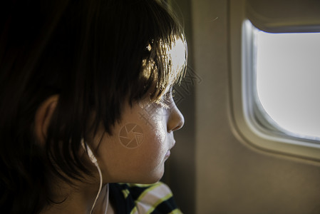 男孩在飞机上透过飞机窗看外面图片