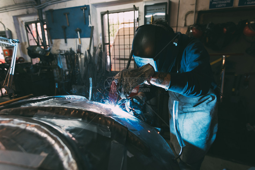 带着焊接面罩在金属铸造车间焊接金属的工人图片