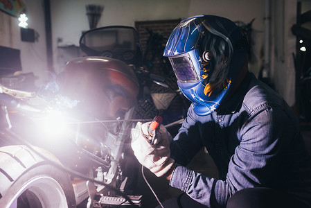 车库中的成熟男子用焊接设备修摩托车图片