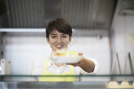 在快餐店向顾客提供食品的年轻妇女图片