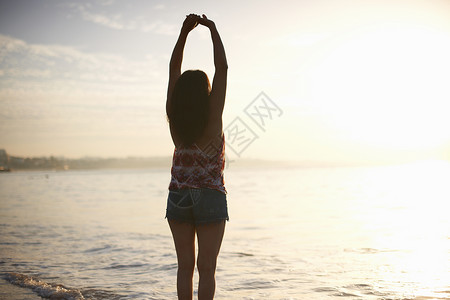 妇女举起双手站在海边图片