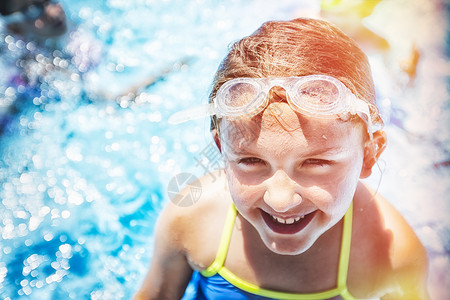 阳光下游泳池里的女孩在微笑图片
