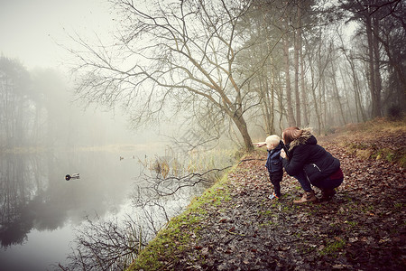 蹲在湖边看的风景的妈妈和孩子图片