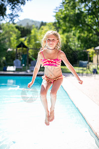 女孩跳入户外游泳池的肖像阳光高清图片素材