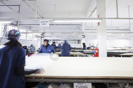女工在服装厂展开纺织品图片