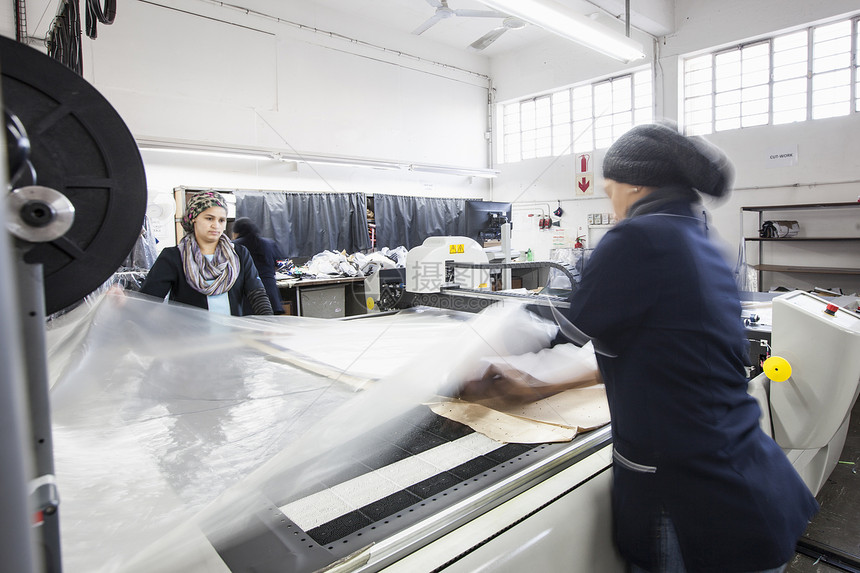 工厂女在服装厂中将纺织脱到裁制机图片
