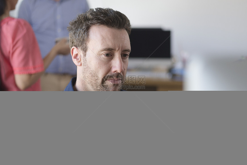 在办公桌使用计算机工作的男性图片