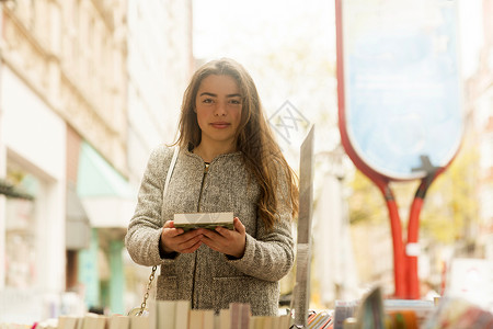 在市场摊位拿着图书的年轻女子肖像图片