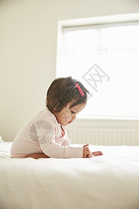 坐在床上玩脚的婴儿女孩图片