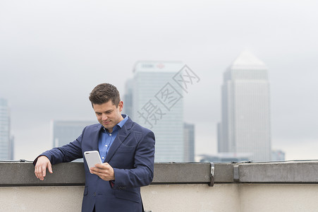 在英国伦敦市办公楼露台看手机的商人图片