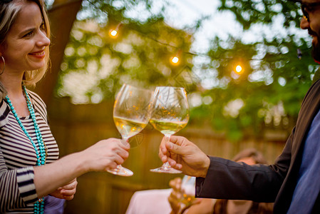 在花园派对上的男人和女拿着葡萄酒杯敬酒微分聚焦高清图片素材