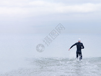 穿潜水服的男性跑向海面图片