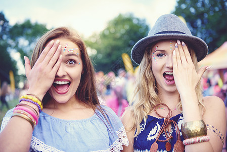 两位年轻女人在音乐节面对镜头遮住眼睛背景图片