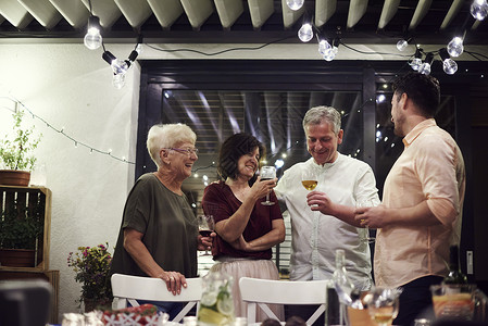 一群人站在晚餐桌边拿着葡萄酒杯70至74岁高清图片素材