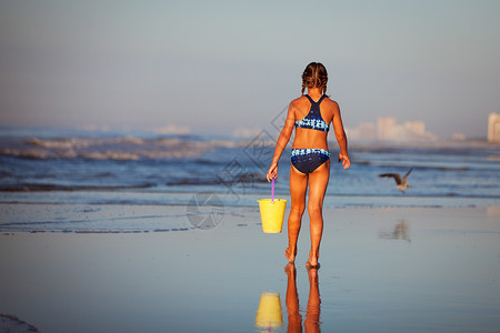 北默特尔海滩海滩上拎着水桶的女孩的背影背景