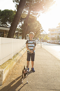 街上带着狗的男孩肖像看着镜头微笑图片