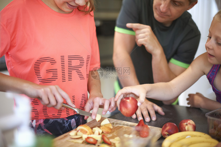 女孩和家人在厨房切碎新鲜水果图片