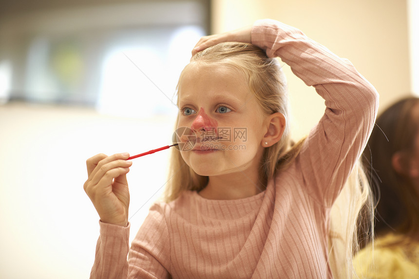 年轻女孩在脸上涂颜料图片