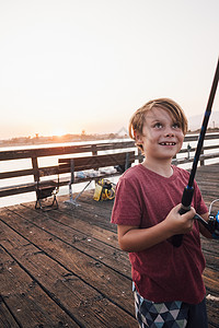 美国加利福尼亚州戈莱塔北美洲码头上的男孩微笑着拉着鱼竿图片