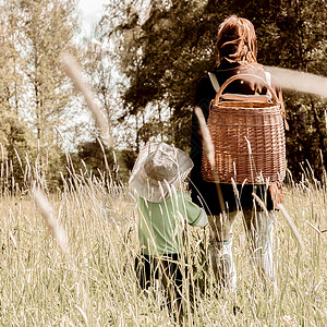 田野中背着竹筐漫步的母子图片