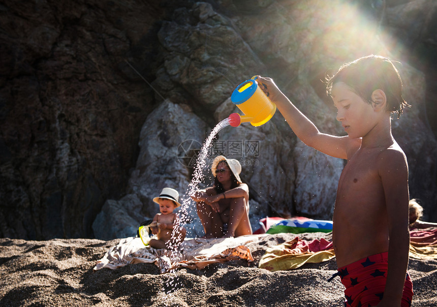 海滩上的男孩在洒水壶图片
