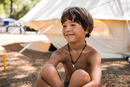 坐在露营地上微笑的男孩图片