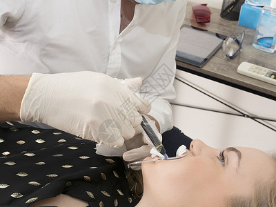 年轻女牙医在给年轻女性做口腔手术图片