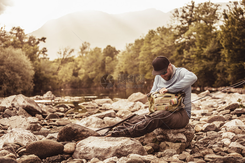 斯洛文尼亚布雷佐维卡莫齐耶坐在河石上搜寻渔袋的渔民图片