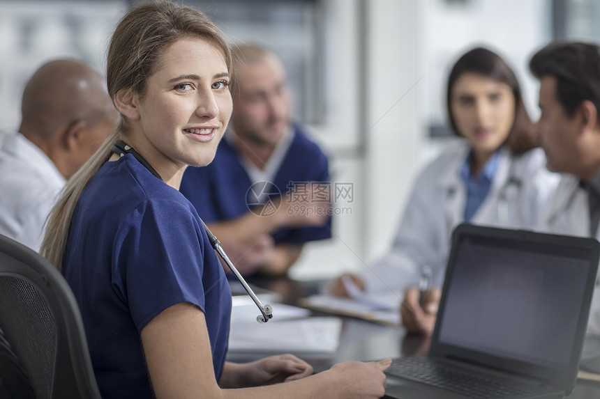 坐在桌边的一组医生里一个回头看的女医生图片