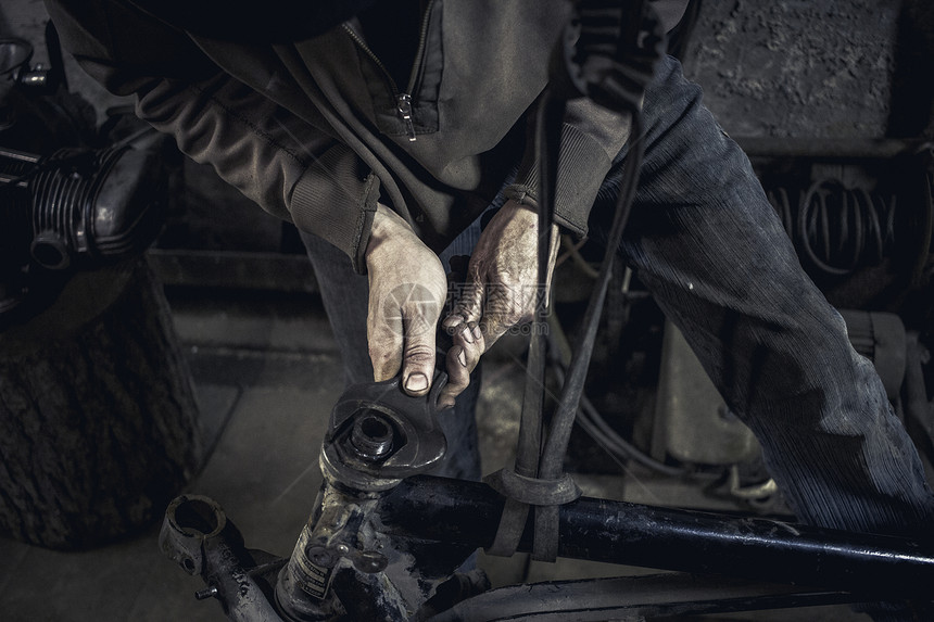 在车间中男人修理老式摩托车的手图片