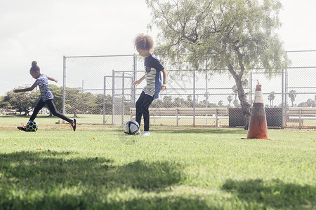 在学校草地上踢足球的女学生图片