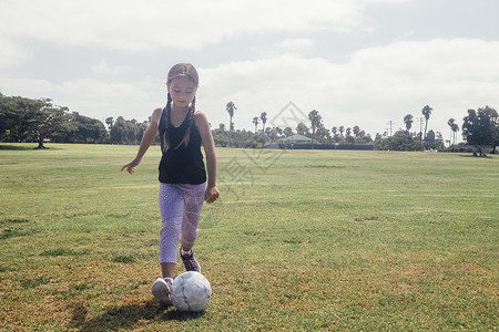 在学校草地上踢足球的女孩图片