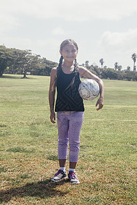 在学校草地上抱着足球的女学生形象图片