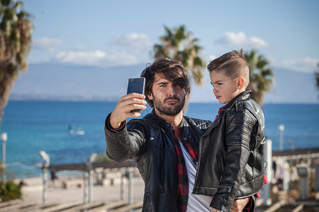 父亲和儿子户外父亲用智能手机自拍图片