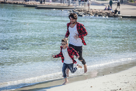 父亲和儿子在海滩上奔跑图片