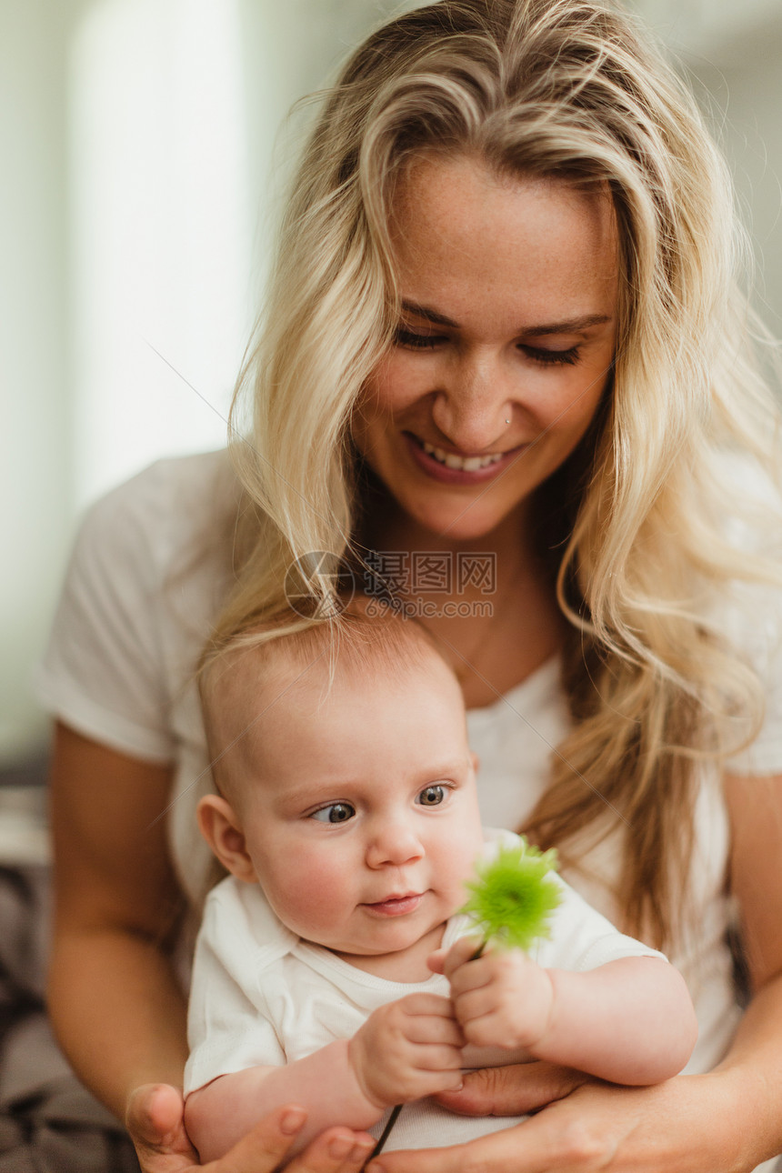 坐在母亲大腿上看着花的女婴儿图片