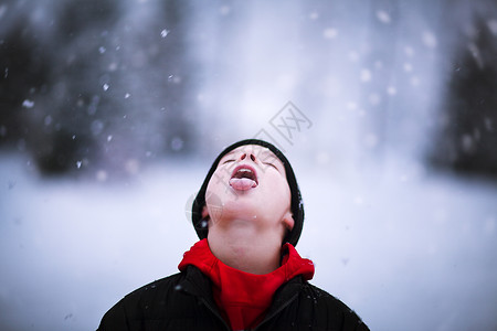 男孩的肖像在舌头上抓着落雪背景图片