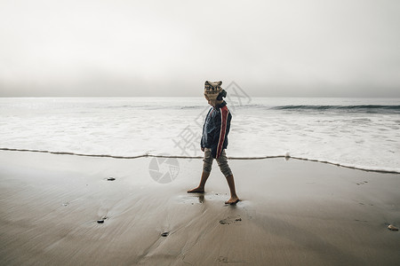 年轻男孩站在沙滩上看远了图片